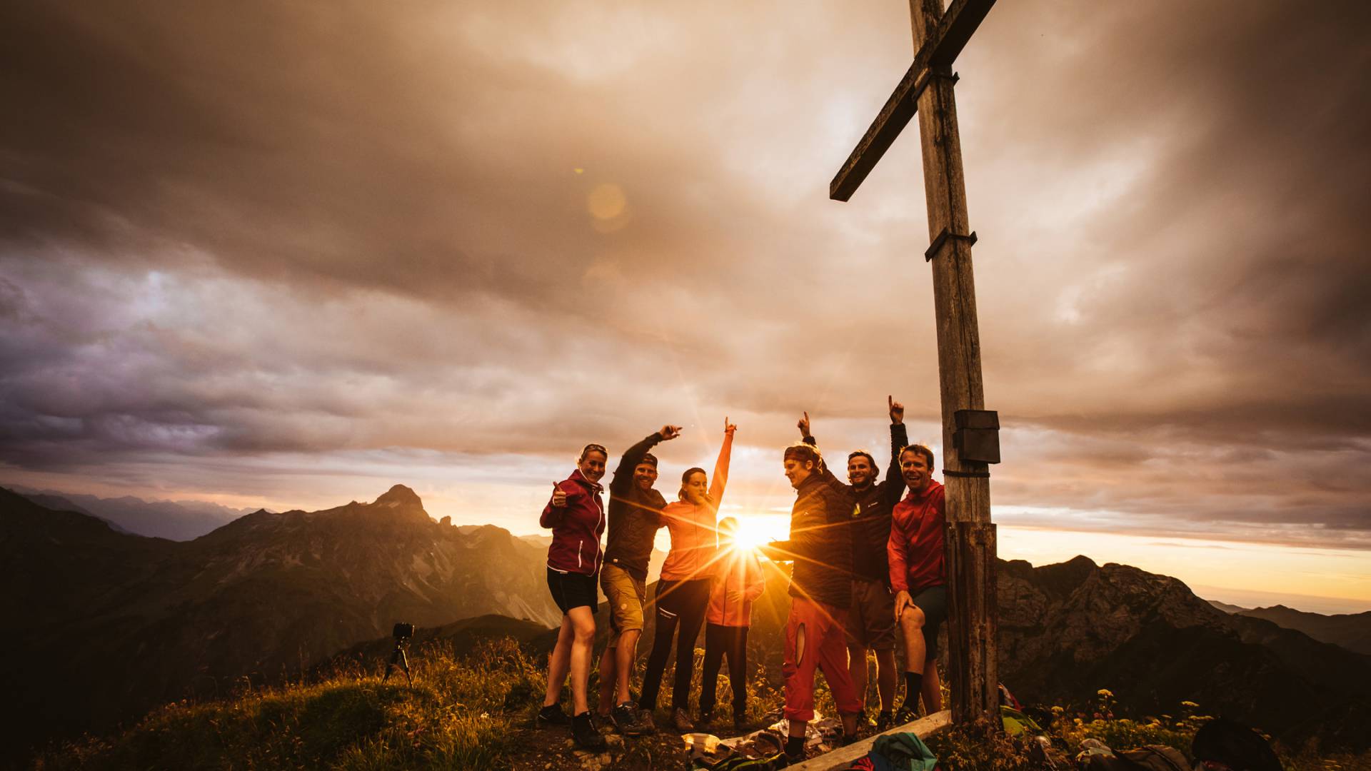 Group at a summit cross during sunset on a summer holiday in Warth am Arlberg.