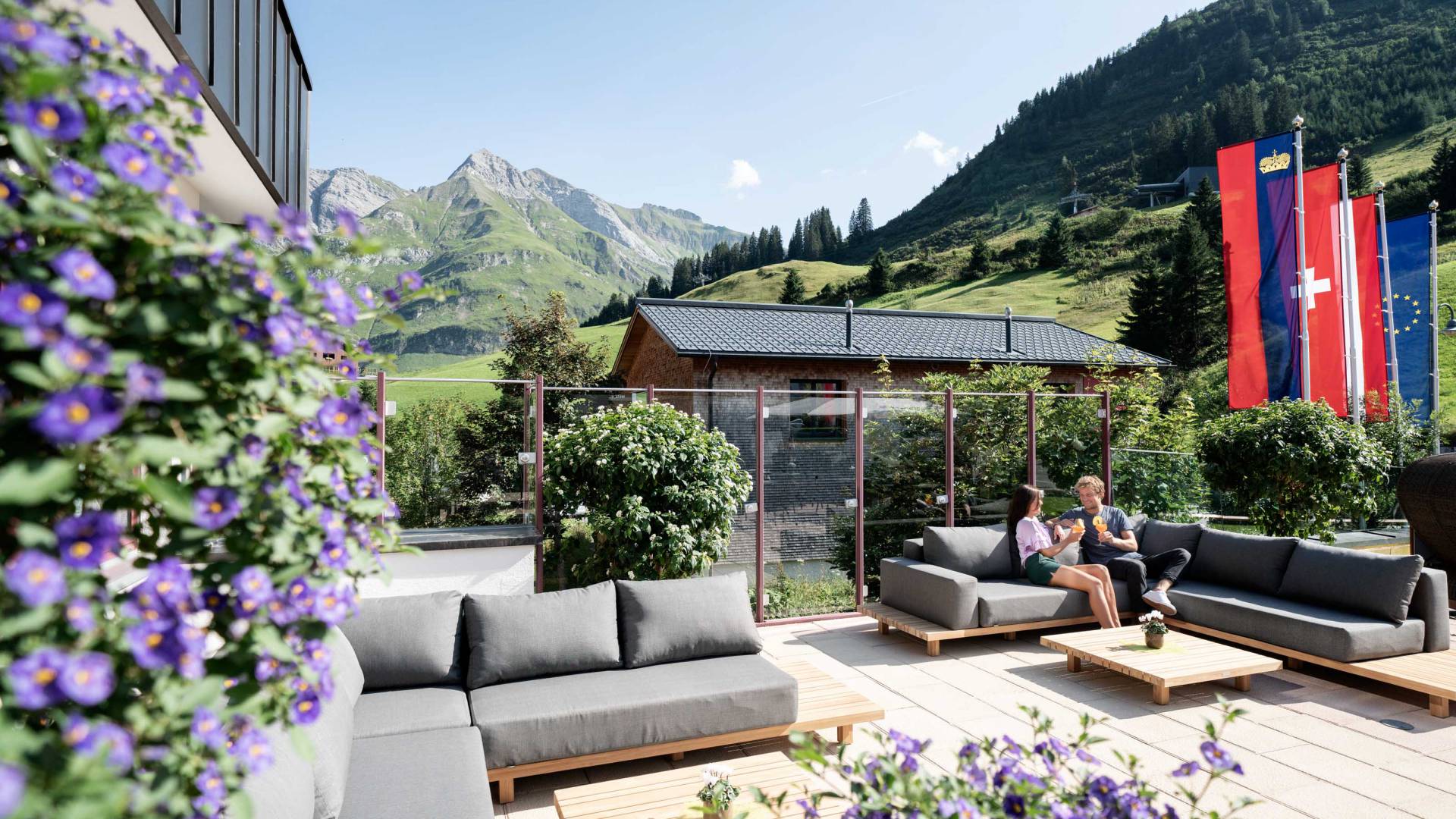Sun terrace with cozy lounge seating and mountain views at the Wellnesshotel Warther Hof in Warth on the Arlberg.