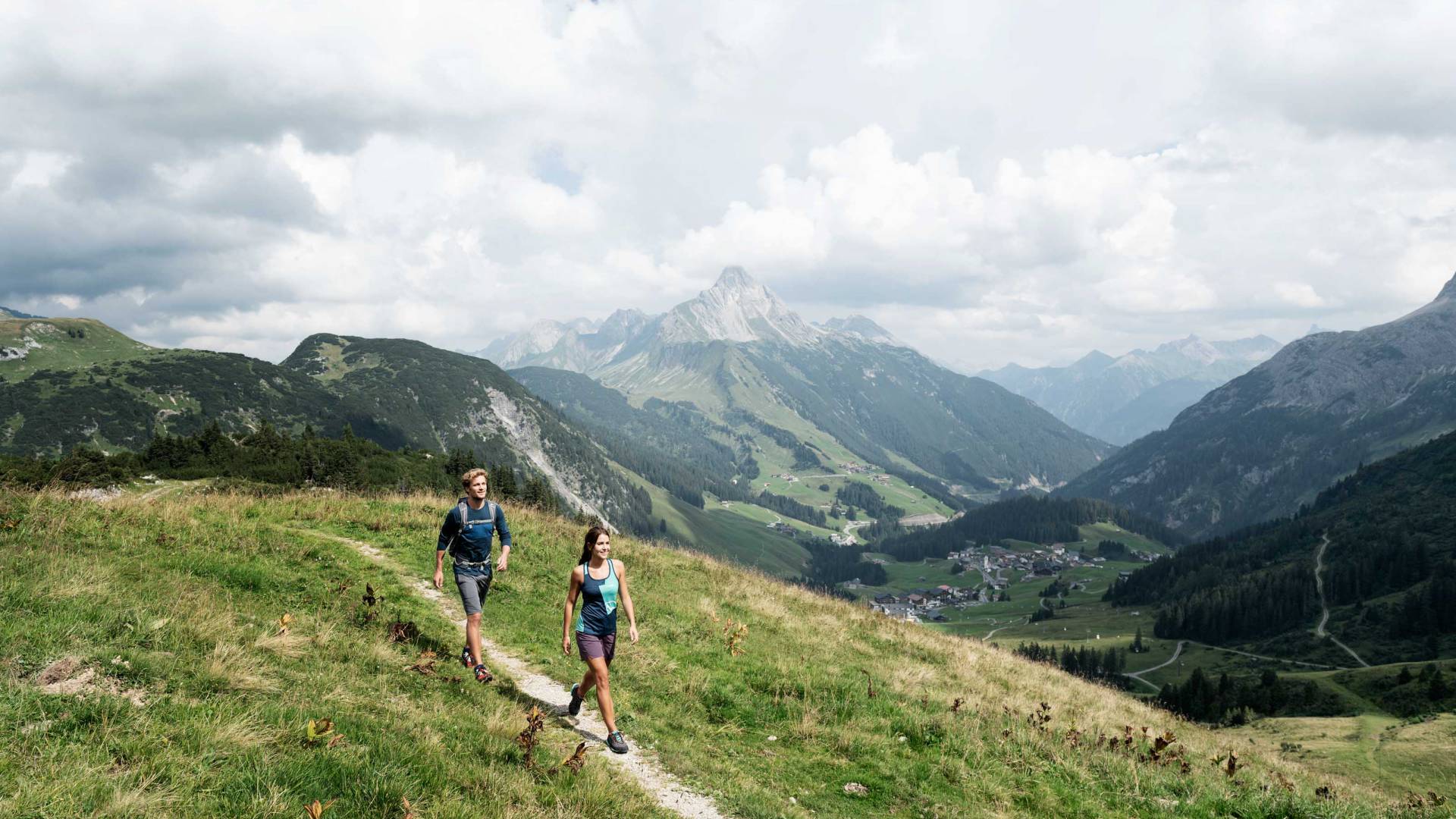 Wanderer auf Höhenweg mit Blick auf die Alpenlandschaft rund um Warth am Arlberg.