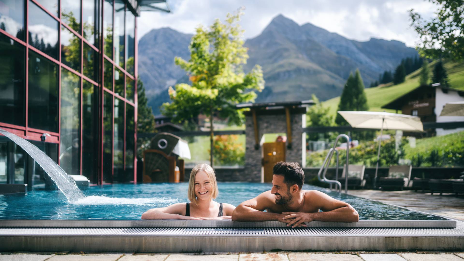 Pärchen im Außenpool im Wellnesshotel Warther Hof mit Blick auf die Alpen.