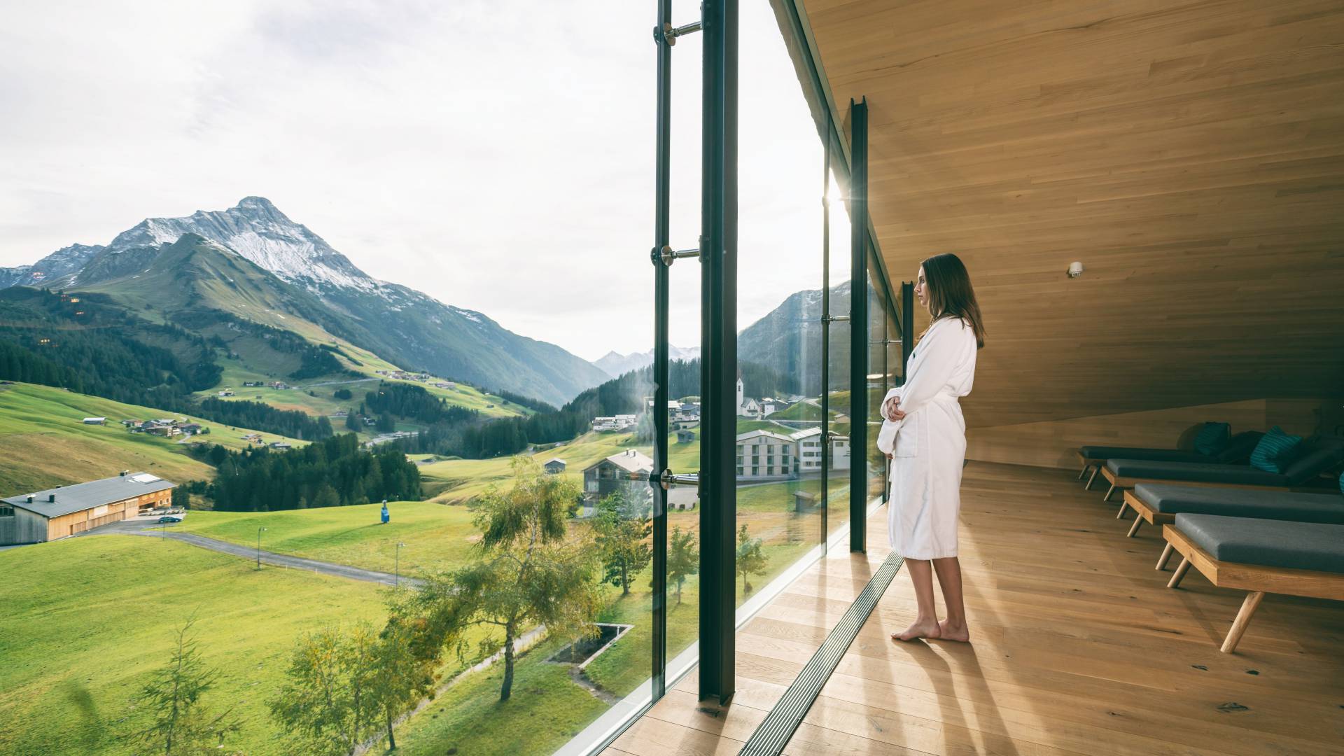 Frau blickt aus Fenster mit Aussicht auf den Arlberg